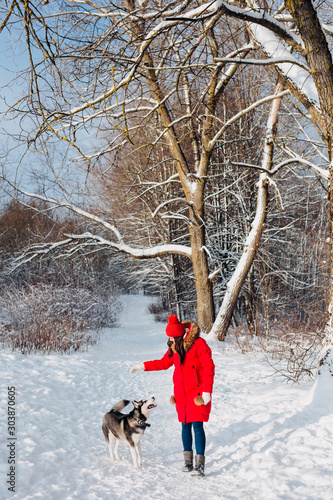 Portrait of a young woman with dog husky on winter walk.