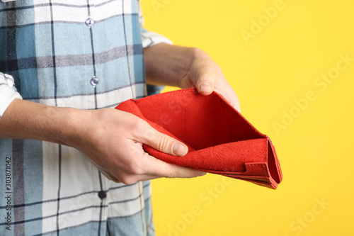 Woman showing empty wallet on yellow background, closeup