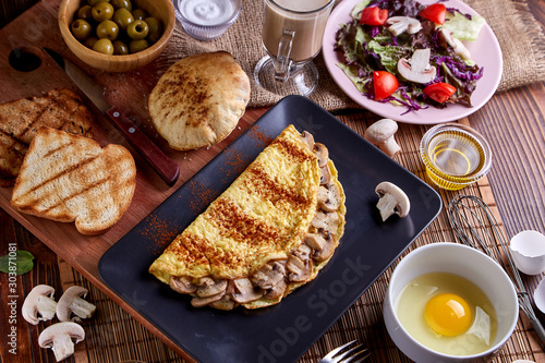 Mushroom omelette in black plate on wood table