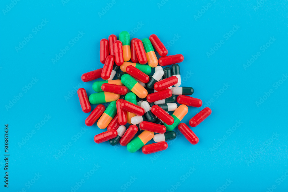 A heap of mixed colored pills on a blue background A heap of mixed colored pills on a blue background