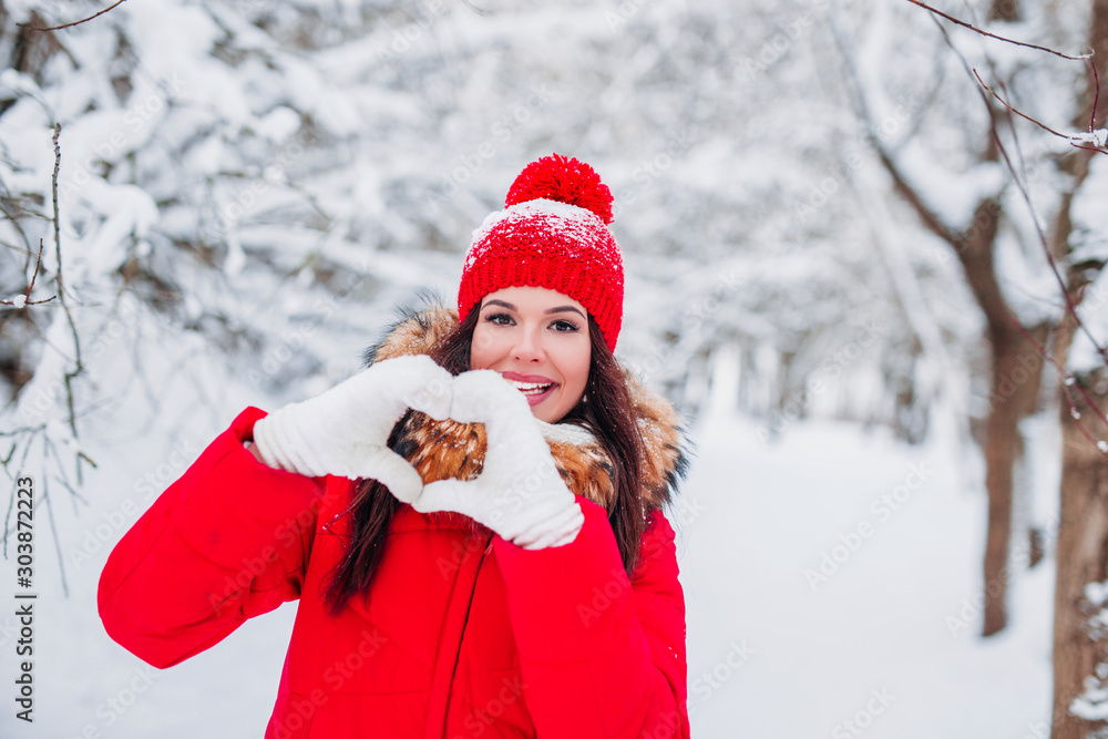 Pretty romantic young woman making a heart gesture with her fingers on winter background Pretty romantic young woman making a heart gesture with her fingers on winter background