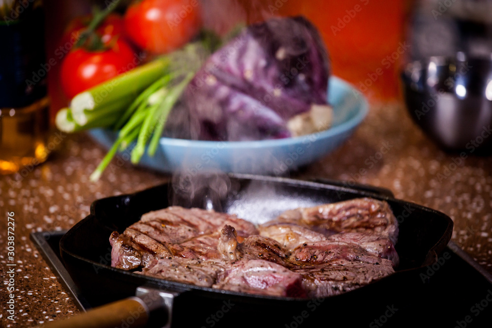 grilled steak in a frying pan on a background of vegetables