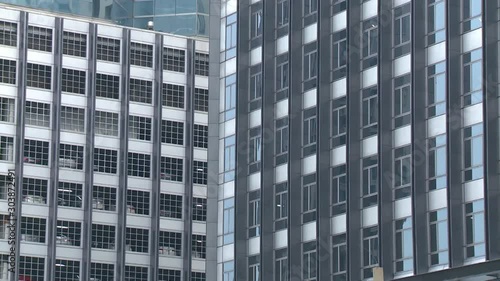 A closeup shot with a zooming view of some tall buildings with paneled glass window facade located in Bangkok, Thailand. photo