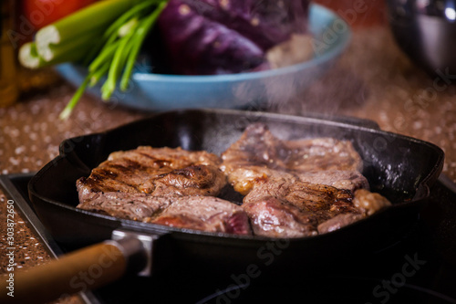 grilled steak in a frying pan on a background of vegetables