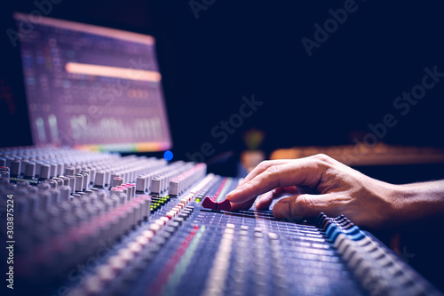 male producer, sound engineer hands working on audio mixing console in broadcasting, recording studio photo