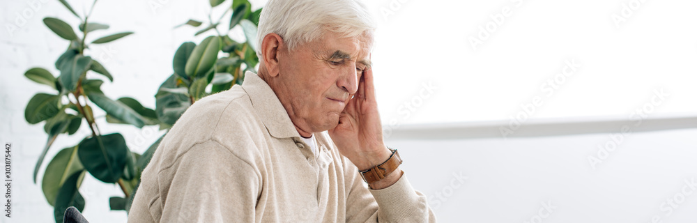 panoramic shot of senior man having headache in apartment panoramic shot of senior man having headache in apartment