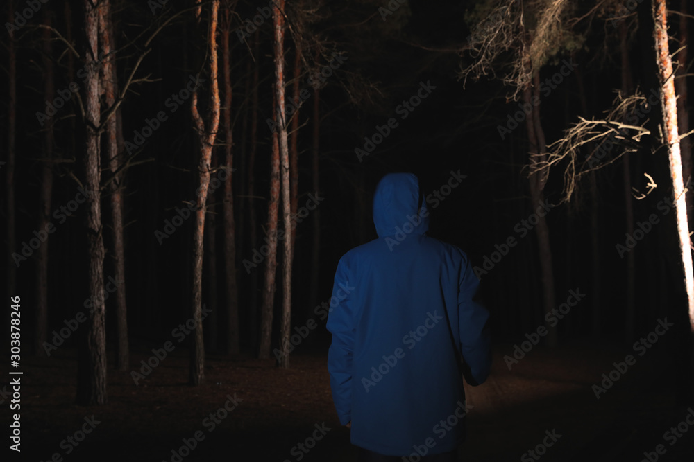Man with bright flashlight in forest at night Man with bright flashlight in forest at night