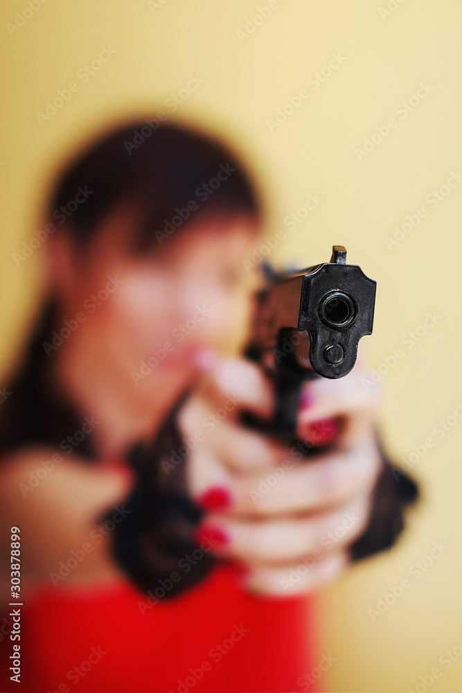 Blurred Girl in Red Dress pointing Plastic Toy Gun. Selective Focus on the Barrel. Bond girl Blurred Girl in Red Dress pointing Plastic Toy Gun. Selective Focus on the Barrel. Bond girl