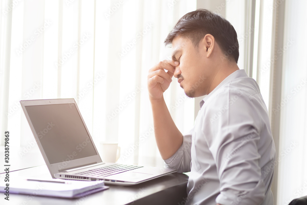 Asian business people are feeling stressed about the job with laptop and paper on the wooden table in the office. Asian men are worried when their work is unsuccessful. Asian business people are feeling stressed about the job with laptop and paper on the wooden table in the office. Asian men are worried when their work is unsuccessful.