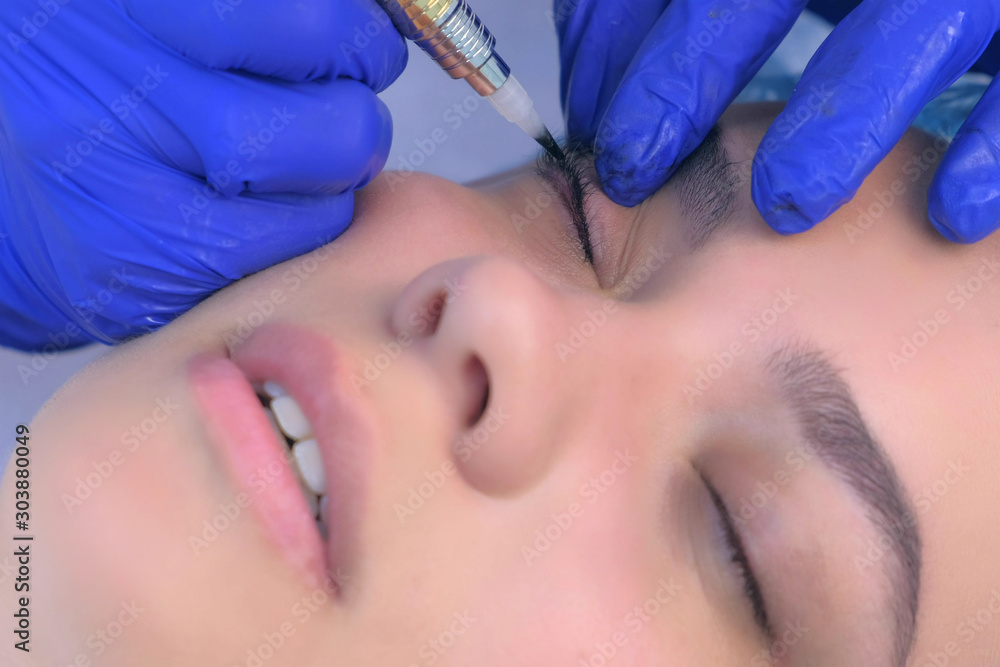 Premanent eyeliner on eyelids for young woman in beauty clinic, closeup face. Cosmetologist making beauty procedure for young woman in clinic, hands closeup. Premanent eyeliner on eyelids for young woman in beauty clinic, closeup face. Cosmetologist making beauty procedure for young woman in clinic, hands closeup.