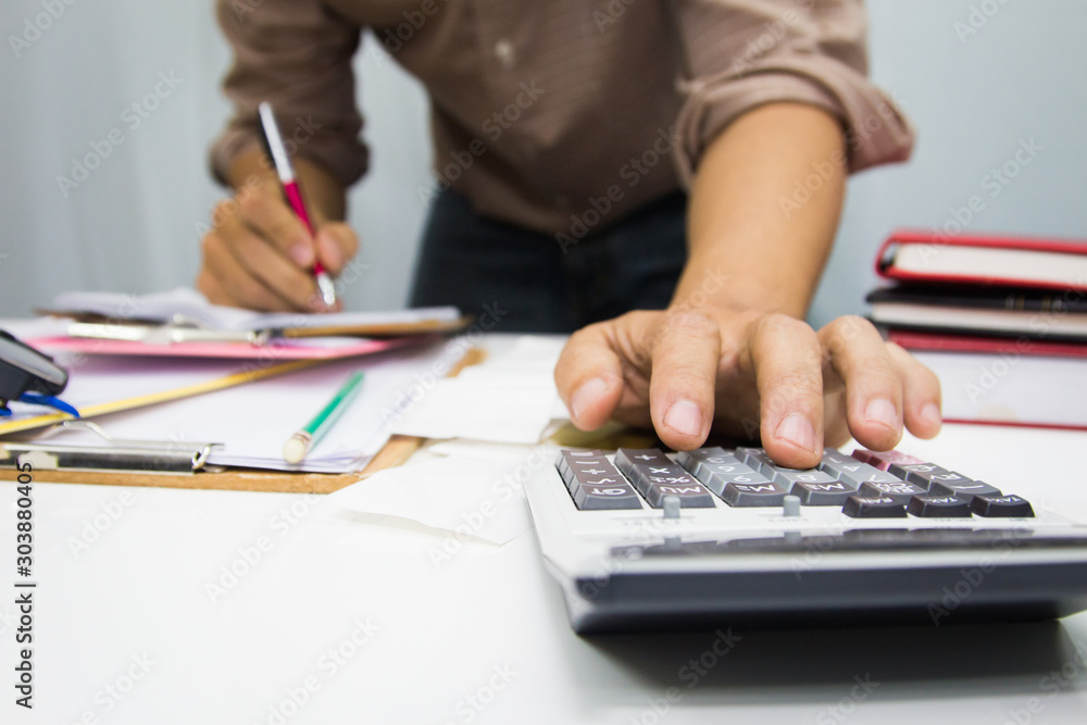 businessman using calculator and holding pen on tax paper in office.Accounting.concept. businessman using calculator and holding pen on tax paper in office.Accounting.concept.