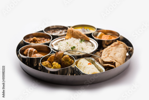 Indian vegetarian Food Thali or platter includes paneer butter masala  dal makhani   tarka  chole papad  kofta curry  gulab jamun  aloo-gobi sabji  chapati and rice with Bengali sweet served