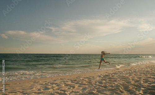 Girl Dancing on the Beach in the sand by the surf at sunset