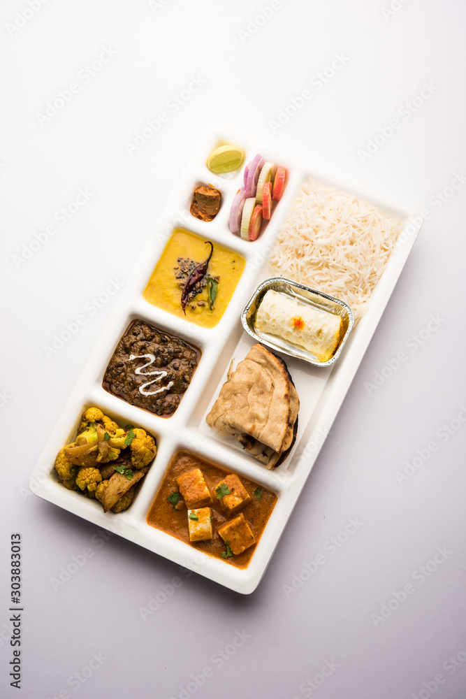 Indian vegaterian Food Thali or Parcel food-tray with compartments in which paneer, dal makhani / parka, aloo-gobi sabji, chapati and rice with Bengali sweet served Indian vegaterian Food Thali or Parcel food-tray with compartments in which paneer, dal makhani / parka, aloo-gobi sabji, chapati and rice with Bengali sweet served