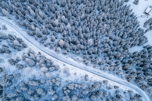Aerial view of Curved road in the snowy mountains of Italian Alps in South Tyrol, during winter / Sunny winter day with harsh shadows and lot of snow