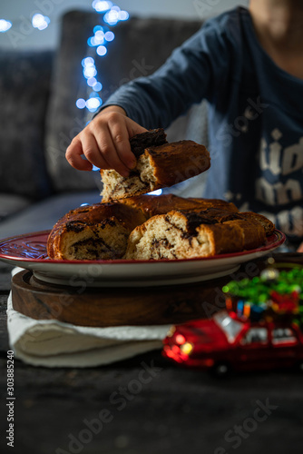 chocolate babka, a dessert on a red festive plate, Christmas light on background, toddler's hands photo