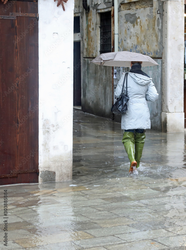 Woman with umbrella and big boot during the flood