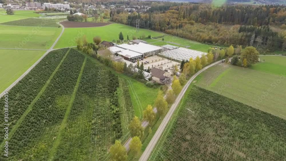 Drone aerial view of a greenhouse surrounded by green paddocks next to a village in Uitikon, Switzerland. Drone aerial view of a greenhouse surrounded by green paddocks next to a village in Uitikon, Switzerland.