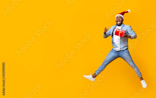 Funny black man jumping with christmas gift box