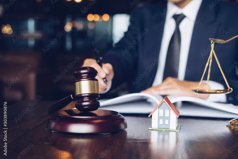 Real Estate Law concept. Gavel on sounding block in hand's Male judge at a courtroom, working for the insurance compensations. report the case on table in modern office. Real Estate Law concept. Gavel on sounding block in hand's Male judge at a courtroom, working for the insurance compensations. report the case on table in modern office.