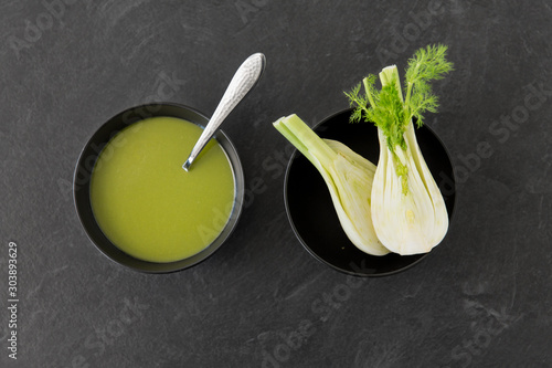 vegetable, food and culinary concept - fennel cream soup in ceramic bowl on slate stone background