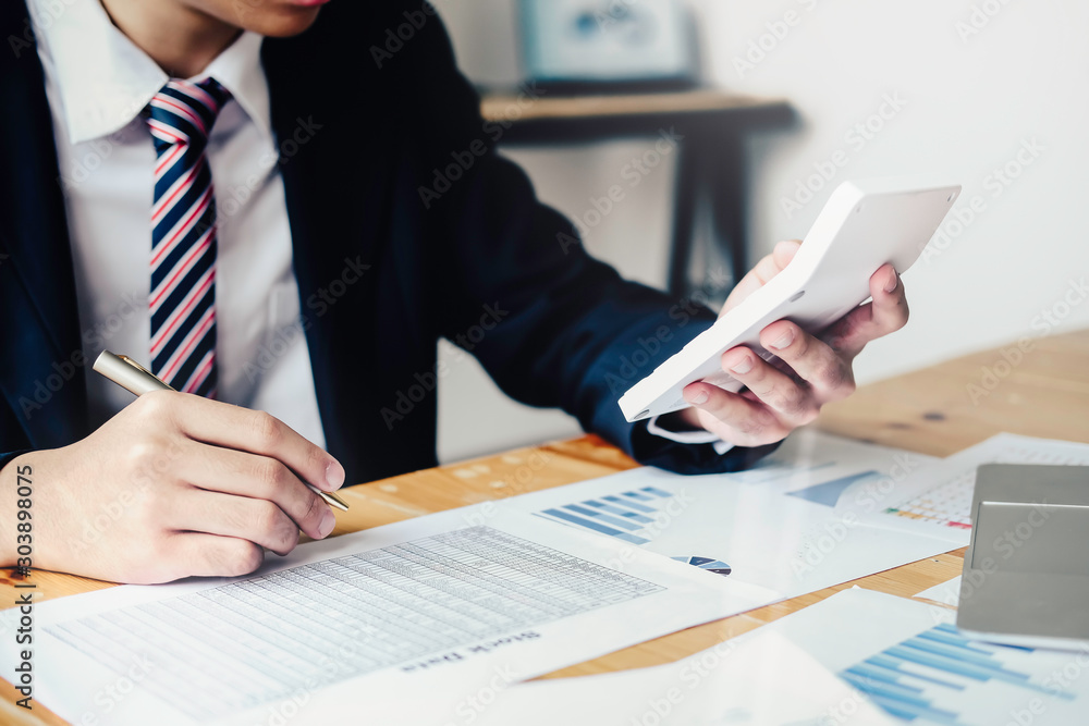 Φωτογραφία asian businessman or accountant working pointing graph discussion and analysis data charts and graphs and using a calculator to calculate  numbers