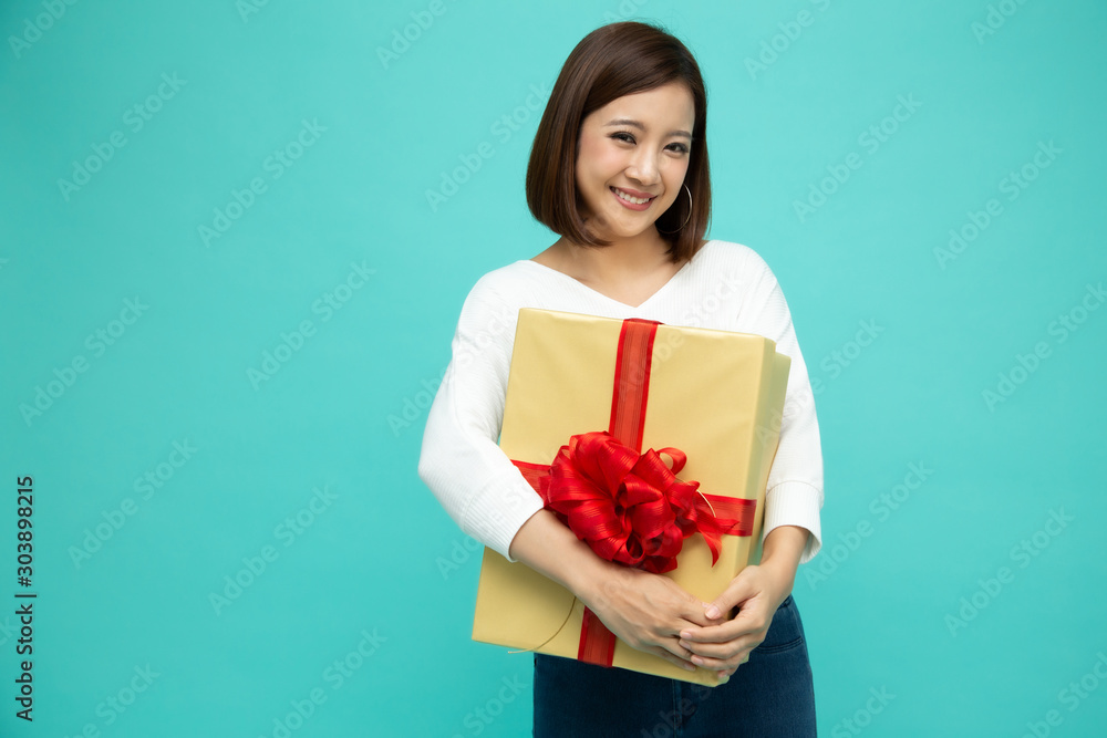 Happy beautiful asian woman smile with gold gift box isolated on light green background. Teenage girls in love, Receiving gifts from lovers. New Year, Christmas and Valentines Day concept Happy beautiful asian woman smile with gold gift box isolated on light green background. Teenage girls in love, Receiving gifts from lovers. New Year, Christmas and Valentines Day concept