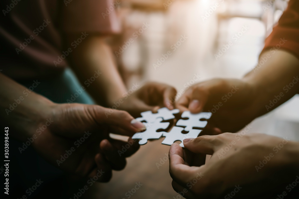 Closeup hand of business people connecting jigsaw puzzle with sunlight effect, Business solutions and represent team support and help concept, success and strategy concept Closeup hand of business people connecting jigsaw puzzle with sunlight effect, Business solutions and represent team support and help concept, success and strategy concept