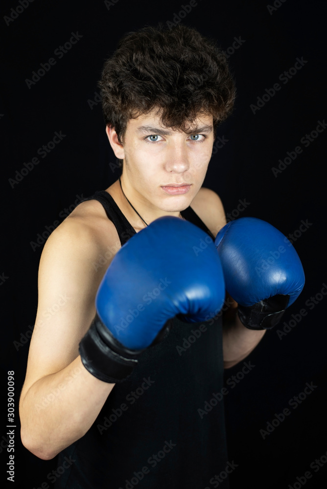 Teenage boy on a dark background with boxing gloves on his hands, the guy is ready to fight with any problems Teenage boy on a dark background with boxing gloves on his hands, the guy is ready to fight with any problems