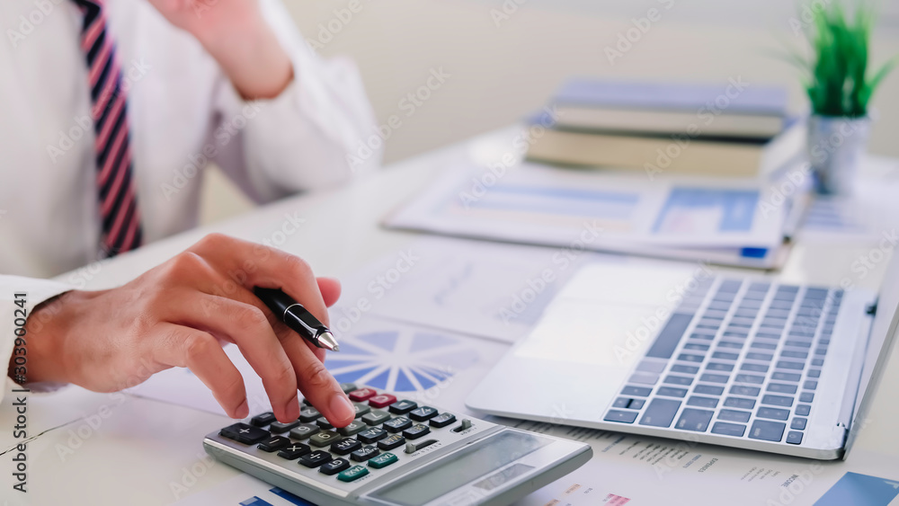 asian businessman or accountant working pointing graph discussion and analysis data charts and graphs and using a calculator to calculate numbers.Business finances and accounting concept asian businessman or accountant working pointing graph discussion and analysis data charts and graphs and using a calculator to calculate numbers.Business finances and accounting concept