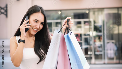 Young woman happy with shopping bags. Easy E-commerce Website Shop by Smartphone, Laptop. Business and modern lifestyle concept