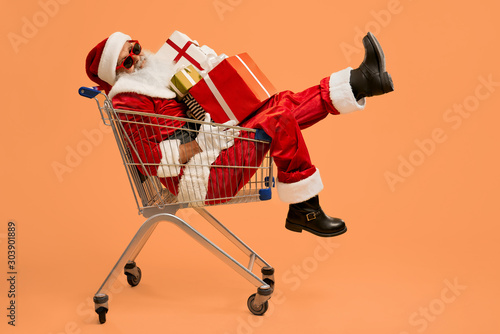 Santa in sunglasses lying in cart with gift boxes in studio © serhiibobyk