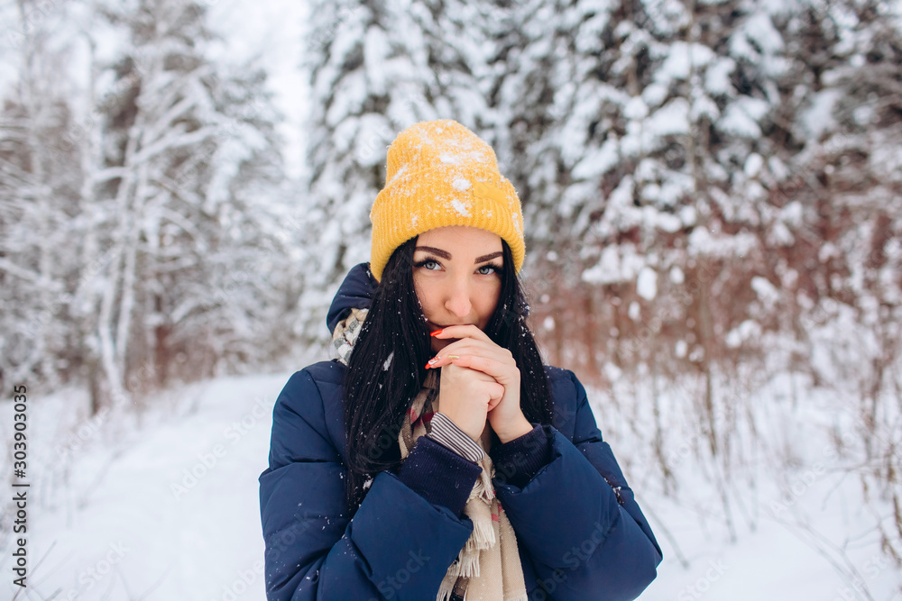 Portrait of a brunette woman in a yellow hat on a background of a winter forest. Closeup portrait of a girl in a snowy park. Portrait of a brunette woman in a yellow hat on a background of a winter forest. Closeup portrait of a girl in a snowy park.