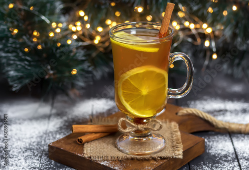 New Year, Christmas drink. Glass of Hot Toddy on wooden table decorated with Christmas tree and Christmas lights. Winter time. Holiday concept. Selective focus