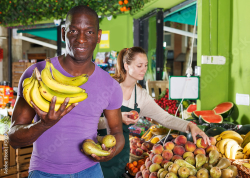 man standing with banana in the fruit market.