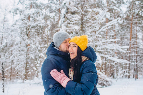 young couple in love walks in the winter forest. active winter holidays. A couple hugs and laughs on a background of a snowy forest. Closeup portrait of a guy and a girl in a snowy forest.