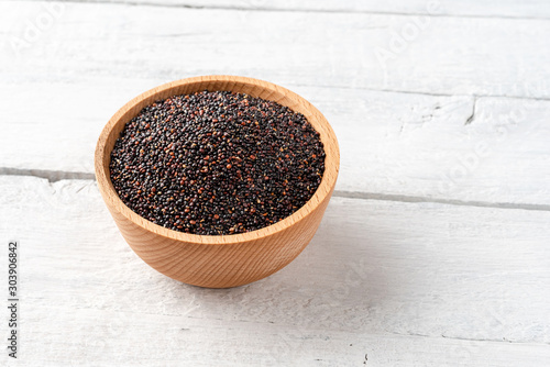 Black quinoa seeds in bowl on vintage wooden background