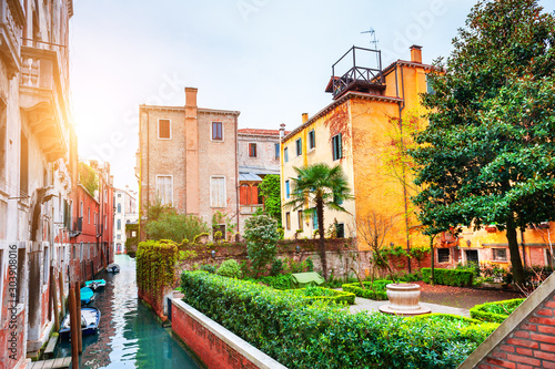 Scenic canal with beautiful green garden in Venice, Italy. Famous travel destination