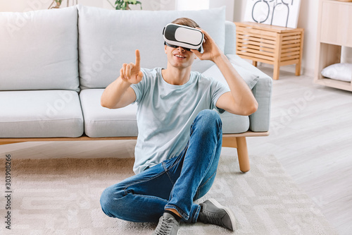 Young man with virtual reality glasses at home © Pixel-Shot