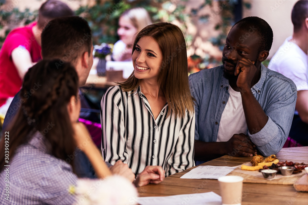 Φωτογραφία Smiling and talking with best friends, sitting around the table on a terrace of