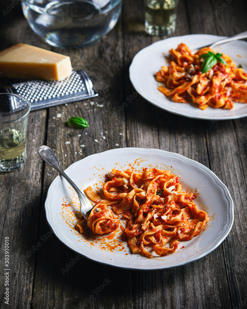 Φωτογραφία White plates full of homemade fresh pasta with tomato and basil sauce, on wooden