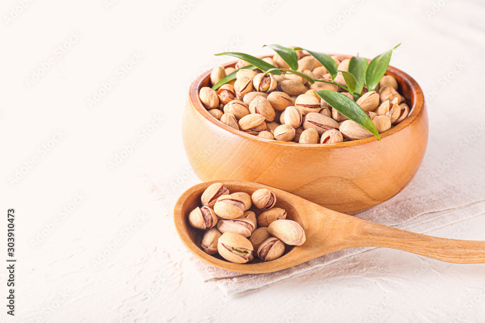 Bowl and spoon with tasty pistachio nuts on table Bowl and spoon with tasty pistachio nuts on table