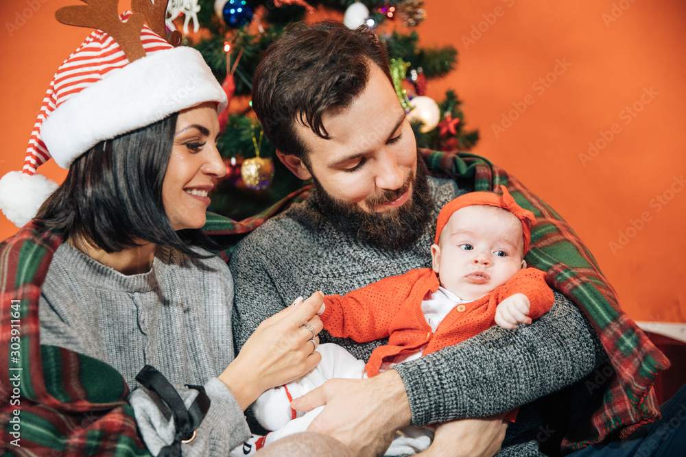 Φωτογραφία young family with a child near the Christmas tree, mom dad and their newborn dau