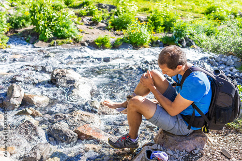 River water and man changing shoes on trail to Ice lake near Silverton, Colorado in August 2019 summer photo