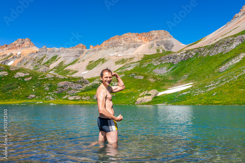 Young fit man flexing standing in cold colorful water of Ice Lake on famous trail in Silverton, Colorado in San Juan Mountains in summer swimming © Kristina Blokhin