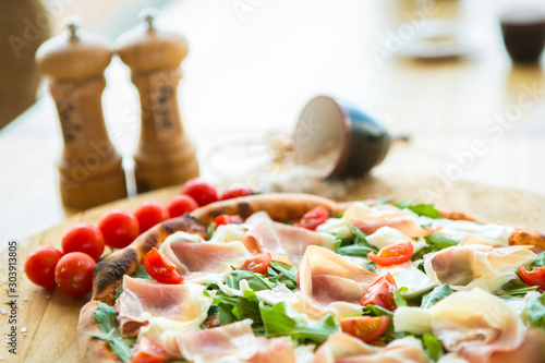 Pizza with cherry tomatoes, prosciutto and ruccola