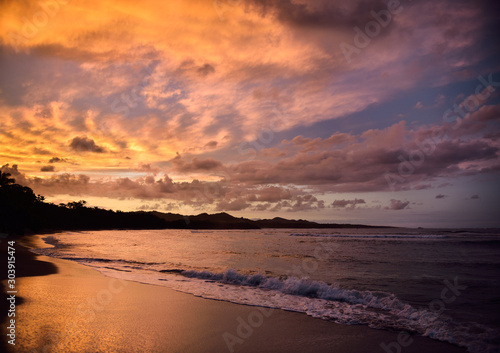 Golden clouds at sunset reflecting off wet beach sand Maimon Bay Dominican Republic