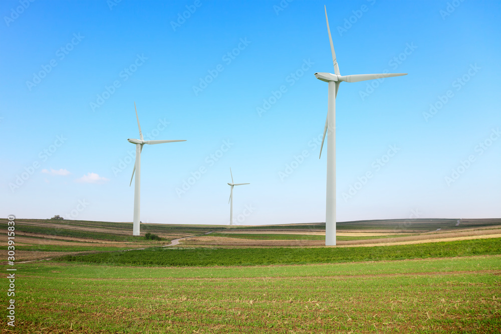 A winding road in a field with a windmills producing electricity A winding road in a field with a windmills producing electricity