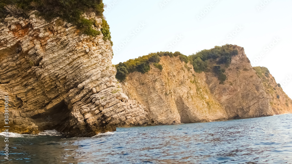 The rocks over the transparent ocean water. Montenegro. Rafailovici.
