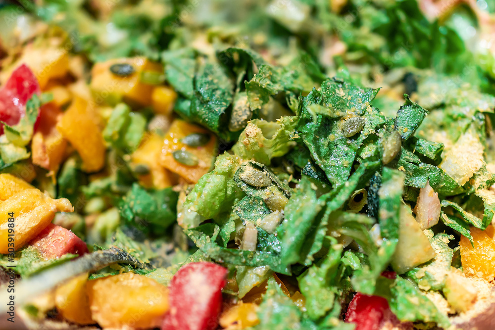 Chopped green vegetables salad macro closeup with fresh vegan romaine lettuce and red tomatoes, yellow bell peppers, and nutritional yeast with pumpkin seeds Chopped green vegetables salad macro closeup with fresh vegan romaine lettuce and red tomatoes, yellow bell peppers, and nutritional yeast with pumpkin seeds